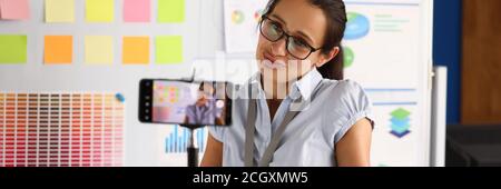Blogger in office is broadcasting online through smartphone. Stock Photo