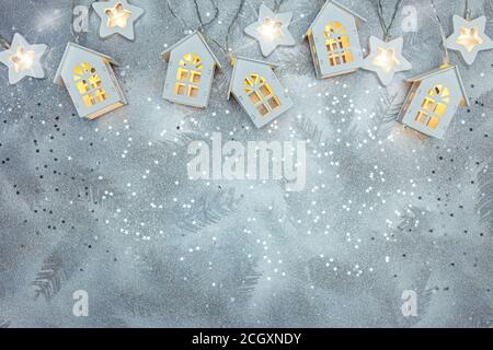 festive new year silver background with wooden home-shaped lights garland Stock Photo