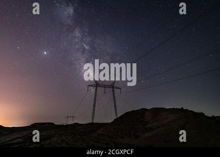 Milky Way galaxy in the night sky above power line supports Stock Photo