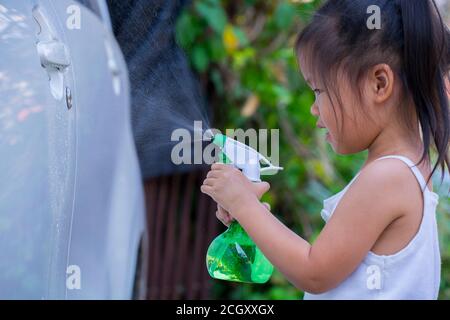 Asian children spry soap to clean car door handle. Stock Photo