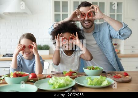Laughing multiracial family making funny faces in kitchen. Stock Photo