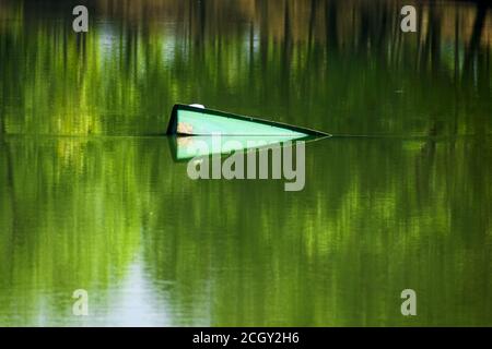 an abandoned and broken boat floats on a lake