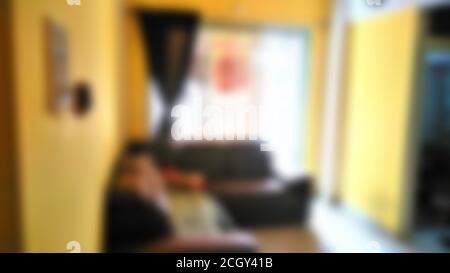 Blur photography. blurred Indian home interior with sofa set, curtain on window, yellow coloured walls with white highlighting.
