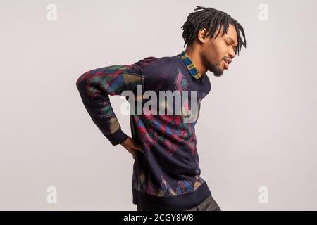 Profile portrait african man with dreadlock cant straighten, suffering from cramped back, health problems, renal colic. Indoor studio shot isolated on Stock Photo