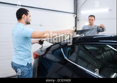 Male workers holds sheet of car tinting, tuning Stock Photo