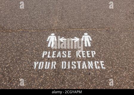 Instructions, please keep your distance, painted on the pavement on the seafront promenade in Sidmouth, a coastal town in Devon on the south coast Stock Photo