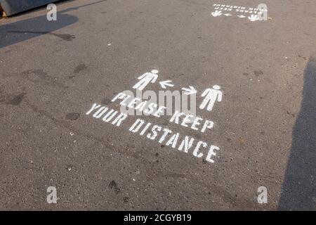 Instructions, please keep your distance, painted on the pavement on the seafront promenade in Sidmouth, a coastal town in Devon on the south coast Stock Photo