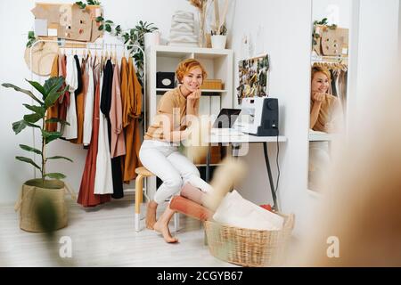 Fashion designer girl in a tailor's studio sitting at a table Stock Photo