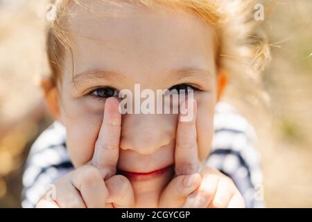 Silly little girl having fun, grimasing, playing with her face Stock Photo