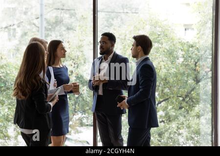 Multiethnic colleagues talk brainstorm in office hallway Stock Photo