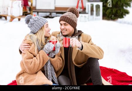 Loving Couple Enjoying Winter Date Outdoors, Sitting On Plaid With Hot Tea Stock Photo