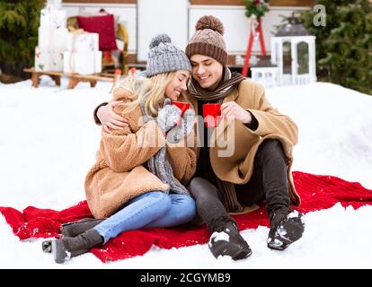 Young Couple Enjoying Hot Drinks During Romantic Date Outdoors On Winter Day Stock Photo