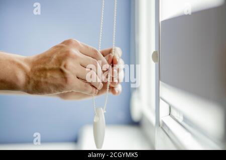 Man testing cassette roller blinds on windows. Stock Photo
