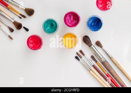 Open gouache jars on white background, flat lay composition,top view.Copy space.Flat lay composition with gouache colors and paintbrushes.advertising Stock Photo