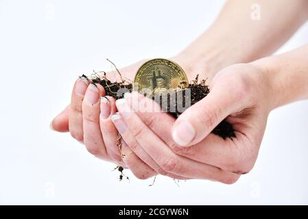 Woman's hands hold black soil and bitcoin. Cryptocurrency mining. Farmer making money Stock Photo