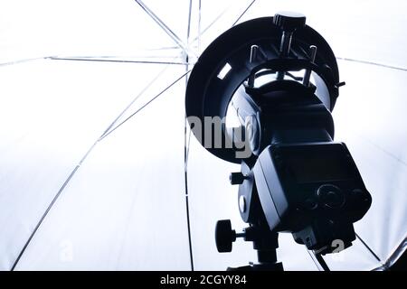 Strobism, on camera system flash on a rack with an umbrella in the studio light. Bright flash light in the studio with a white umbrella on reflection. Stock Photo