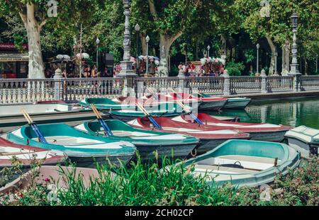 Selective focus on empty rowing boats in Plaza de España with tourists wearing mask in the background.  Covid-19 c Stock Photo