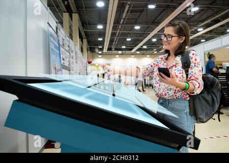 A woman with phone using contactless self service kiosk Stock Photo