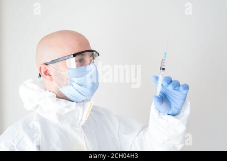 fully sheltered doctor holding syringe in hand. Young doctor preparing for vaccination. Stock Photo