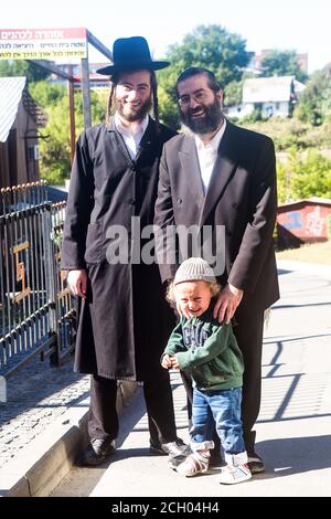 Two smiling Hasidim (hasidic pilgrims) in Uman (Ukraine) w/Jewish kid whose mother asked to photograph her son w/them b4 Rosh-ha-Shana (New Year). Stock Photo