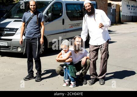 Three smiling Hasidim (hasidic pilgrims) in Uman (Ukraine) w/Jewish kid whose mother asked to photograph her son w/them b4 Rosh-ha-Shana (New Year). Stock Photo