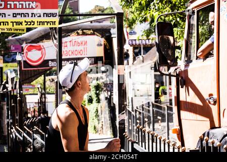 Two workers, one of them a truck driver, former classmates, talk on Pushkin str in Uman (Ukraine) near memorial of Zaddik Nachman attended by Hasidim. Stock Photo