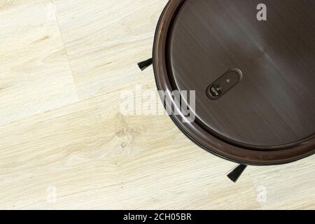 Robot cleaning Home. Automatic Robotic Cleaner On Ground. Overhead black robotic vacuum cleaner tidying tile floor Stock Photo