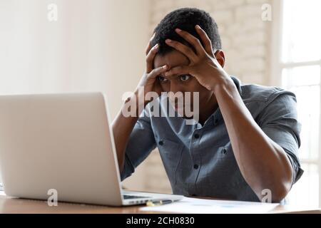 Angry biracial male employee annoyed with laptop operational problems Stock Photo