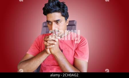 Man sitting on a wooden chair at home with handshake pose. man touching hands on his chin. Stock Photo