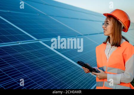 Inspector Engineer Woman Holding Digital Tablet Working in Solar Panels Power Farm, Photovoltaic Cell Park, Green Energy Concept Stock Photo