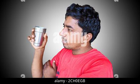 A Man sitting on a chair and drinking tea at home. Indian young man holding tea or coffee cup Stock Photo