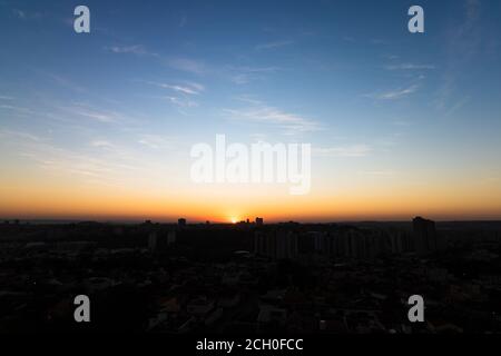 Rising sun with silhouette of buildings on city skyline Stock Photo