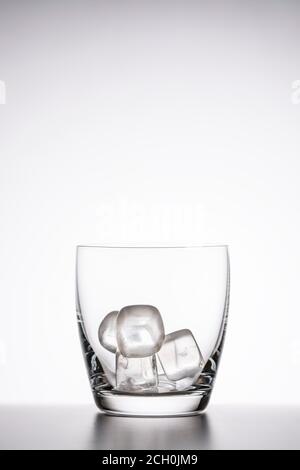 empty clear whiskey glass with ice on a white background. vertical photo, copy space Stock Photo