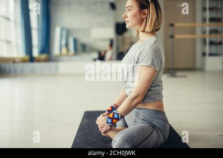 Group of young sporty people practicing yoga lesson with instructor, sitting in vajrasana pose, working out, indoor full length, students training in Stock Photo