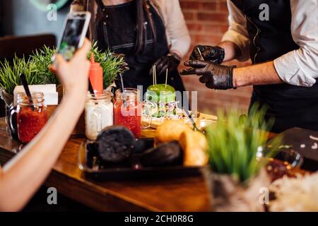 Cropped view of hand making photo on phone as Chef preparing a gourmet burger Stock Photo