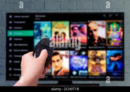 Multimedia streaming concept. female hand holding remote control. TV screen with lot of pictures. Stock Photo