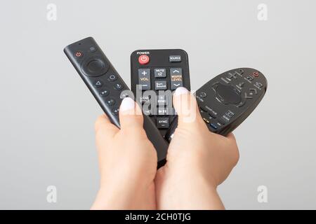 Woman hands with tv remote controls, Many remote control devices in in hands Stock Photo
