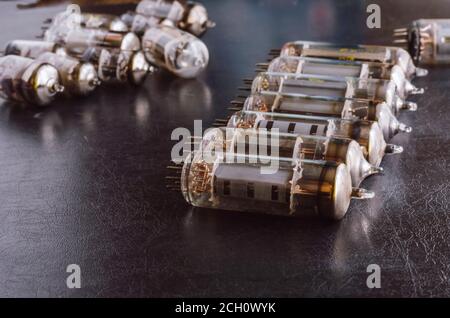 Random vacuum tubes on a black background. A group of radio tubes of different sizes and purposes. Shooting at eye level. Selective focus. Stock Photo