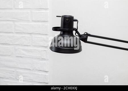 A black table lamp in the interior against a white brick wall Stock Photo