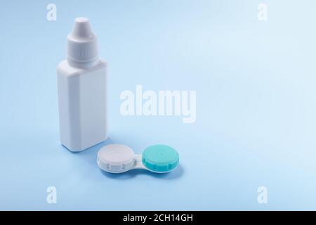 Contact lenses and lens liquid on a blue background. Bottle with lens solution and container for contact lenses. copyspace Stock Photo
