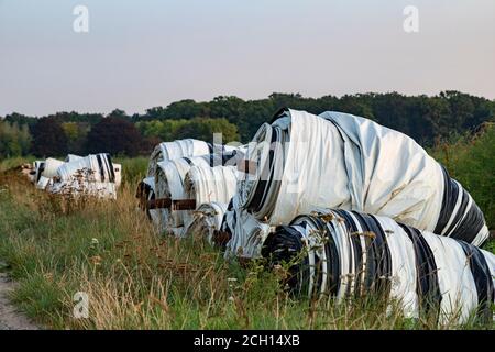 cover tarpaulin, plastic film, rolled up along the roadside for an asparagus field, outdoors