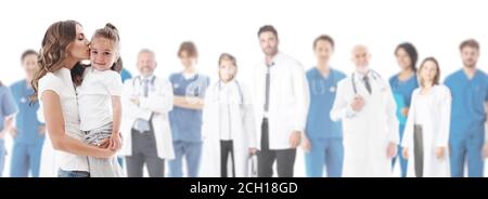 Mother kisses her daughter, team of doctors in medical clinic on background isolated on white Stock Photo