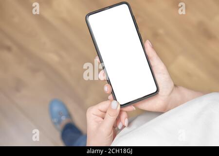 Top view of a woman is using cell mobile phone while is standing on Wooden floor background. Mockup cellphone Stock Photo