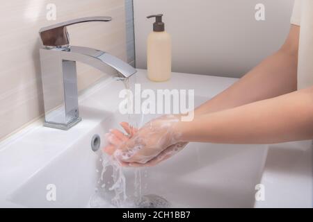 Woman washing hands with soap over sink in bathroom, closeup. Wash hands. Cleaning Hands. Stock Photo
