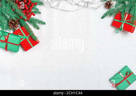 Christmas decor on a white background. Christmas fir branches, gift boxes with red ribbon, red decoration, sparkles and confetti on white background. Stock Photo