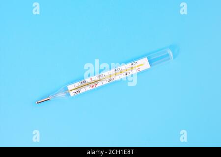 Medical mercury thermometer isolated on blue. Accurate medical thermometerr shows high temperature. Medical thermometer with high temperature indicato Stock Photo