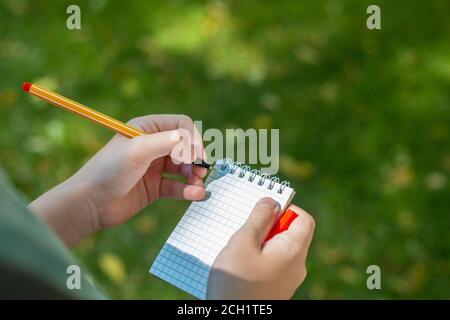 Pen and spiral notepad in hand. Making note. Ideas, plans, checkup. Stock Photo