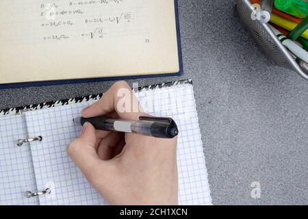 Formula in a book and notebook, hand writes with a ballpoint pen. Performing lessons, training, exercise concept. Stock Photo