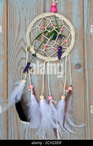 A vertical shot of a red dream catcher hanging from a tree branch in front of a wooden background Stock Photo