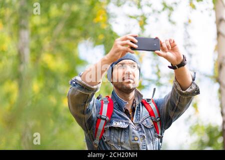 Middle aged hiker taking a photo with his mobile phone. Close up view. Stock Photo